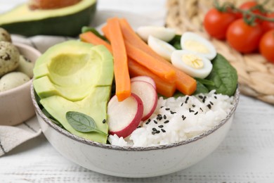 Photo of Delicious poke bowl with basil, eggs, avocado and vegetables on white wooden table, closeup