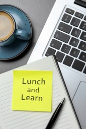 Lunch and Learn concept. Laptop, planner, pen and cup of coffee on grey table, flat lay