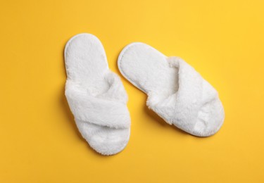 Pair of soft fluffy slippers on yellow background, top view