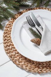 Photo of Stylish festive place setting with plate, cutlery and fir branches on white wooden table