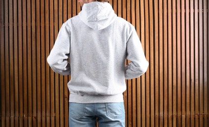 Photo of Man in hoodie sweater on wooden background. Space for design