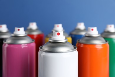 Colorful cans of spray paints on blue background, closeup