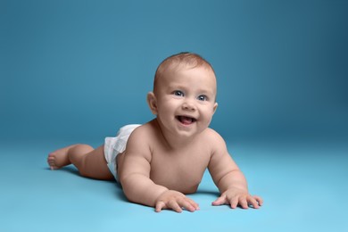 Cute baby in dry soft diaper lying on light blue background