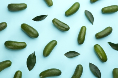 Whole seedless avocados with green leaves on light blue background, flat lay