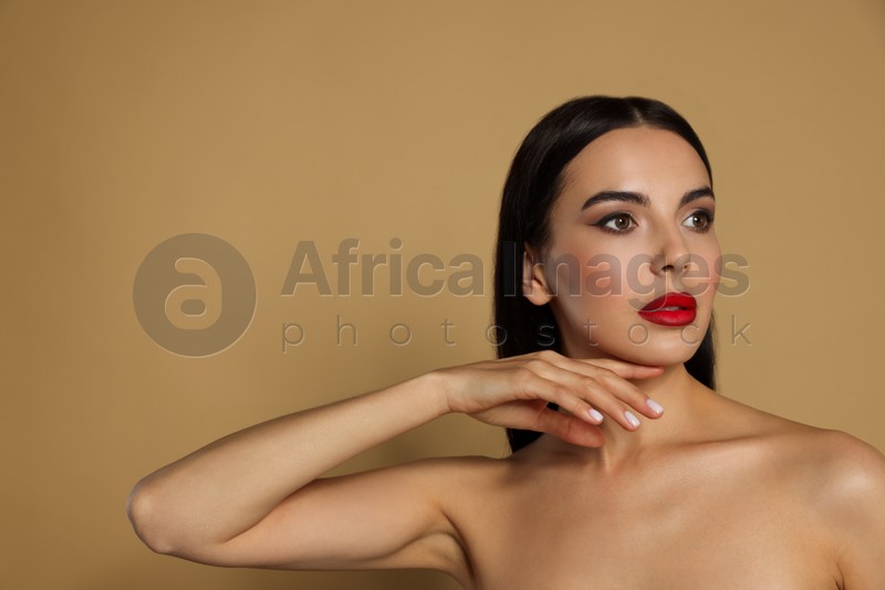 Portrait of young woman wearing beautiful red lipstick on beige background