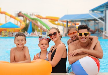 Happy family with inflatable toys in swimming pool at water park