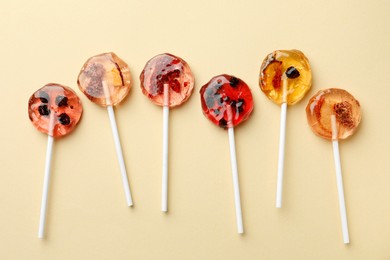 Sweet colorful lollipops with berries on beige background, flat lay