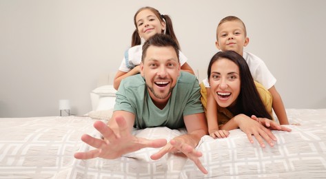 Portrait of happy family with children on bed at home