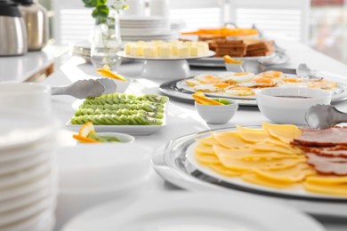 Clean dishware and different meals for breakfast on white table indoors. Buffet service