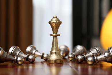 Queen piece among defeated pawns on chessboard indoors