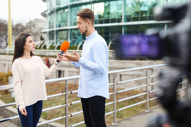 Young journalist interviewing man on city street