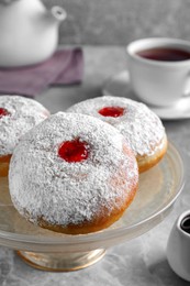 Pastry stand with delicious jelly donuts on grey table, closeup