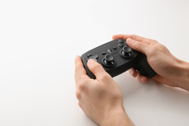 Young man holding video game controller on white background, closeup