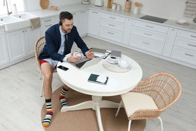 Businessman in underwear pretending to wear formal clothes during video call at home