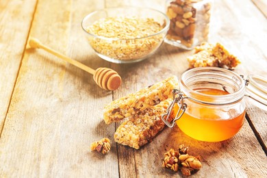 Homemade grain cereal bars and honey on wooden table
