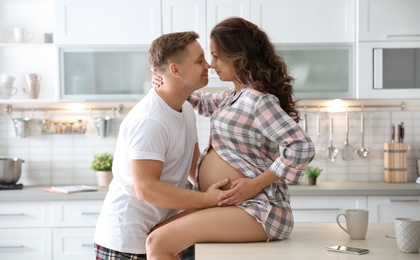 Pregnant woman with her husband in kitchen. Happy young family