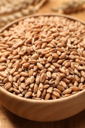Photo of Bowl of wheat grains on wooden table, closeup