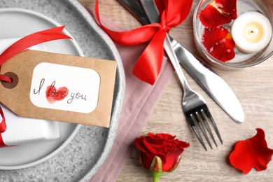 Beautiful place setting and tag with phrase I Love You  on wooden table, flat lay. Valentine's day romantic dinner