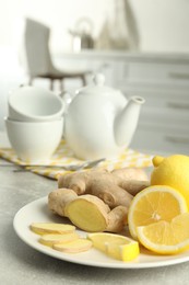 Photo of Fresh lemons and ginger on grey table indoors, space for text