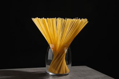 Uncooked spaghetti on grey table against black background. Italian pasta