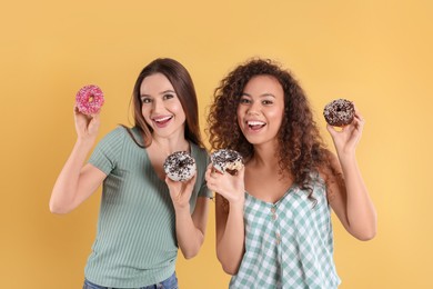 Photo of Beautiful young women with donuts on yellow background