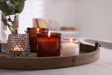 Tray with beautiful burning candles and vase on table indoors