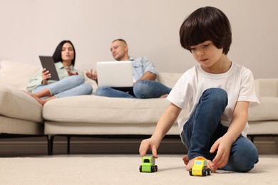 Child playing with toys and parents working on sofa at home