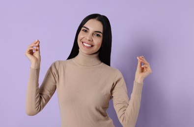 Young woman snapping fingers on violet background