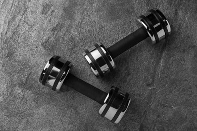 Two dumbbells on grey background, flat lay