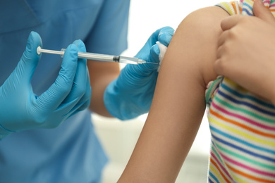 Doctor vaccinating little child in clinic, closeup
