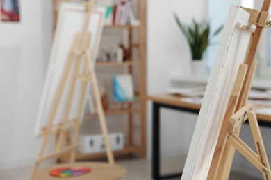 Photo of Wooden easel with canvas in artist's studio, space for text. Creative hobby