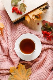 Photo of Flat lay composition with cup of aromatic tea and soft pink sweater on beige textured table. Autumn atmosphere