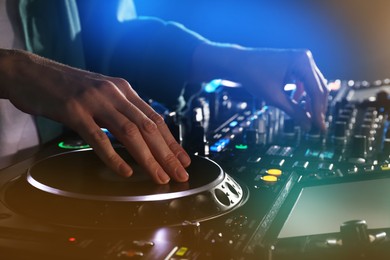 DJ creating music on modern console mixer in night club, closeup