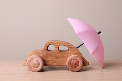 Small umbrella and toy car on wooden table