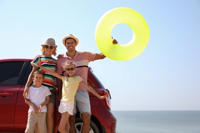 Happy family with inflatable ring near car at beach