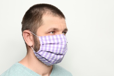Man wearing handmade cloth mask on white background, space for text. Personal protective equipment during COVID-19 pandemic