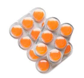 Blisters with orange cough drops on white background, top view
