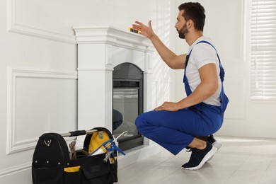 Photo of Professional technician installing electric fireplace in room