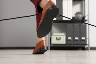 Woman tripping over cable in office, closeup