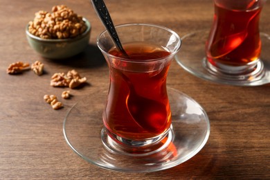 Glasses of traditional Turkish tea and walnuts on wooden table, closeup