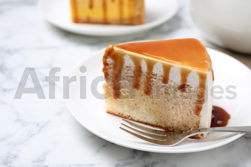Slice of delicious cake with caramel sauce on white marble table