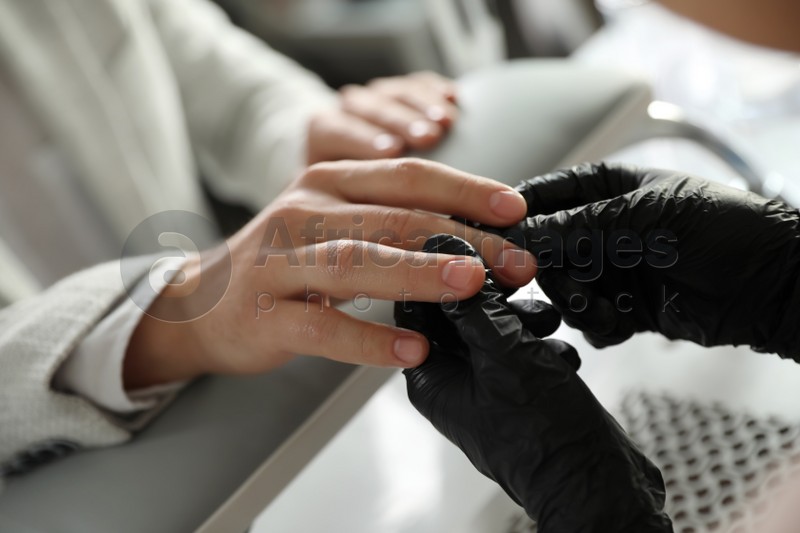 Professional manicurist working with client in beauty salon, closeup