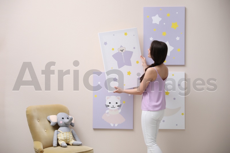 Decorator hanging picture on pink wall. Children's room interior design