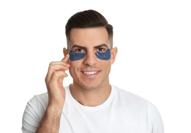 Man applying blue under eye patch on white background