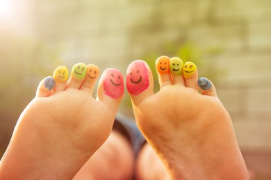 Teenage girl with smiling faces drawn on toes outdoors, closeup