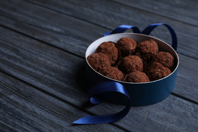 Box with delicious chocolate truffle candies on dark blue wooden table