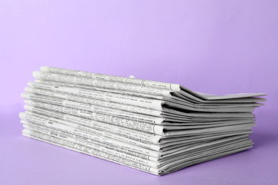 Stack of newspapers on light violet background. Journalist's work