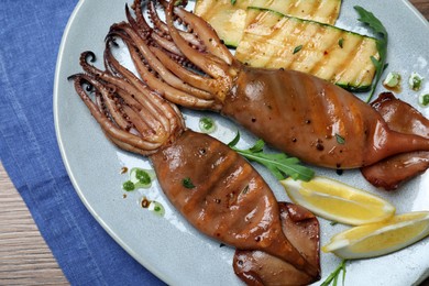 Photo of Delicious grilled squids served on wooden table, top view