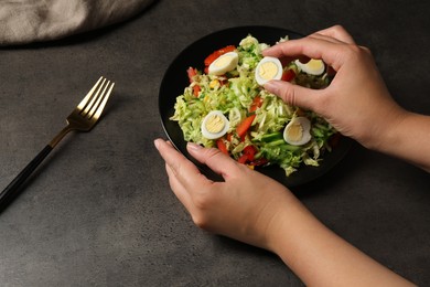 Woman making delicious salad with Chinese cabbage and quail eggs at black table, closeup
