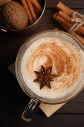 Photo of Delicious eggnog with spices on wooden table, flat lay